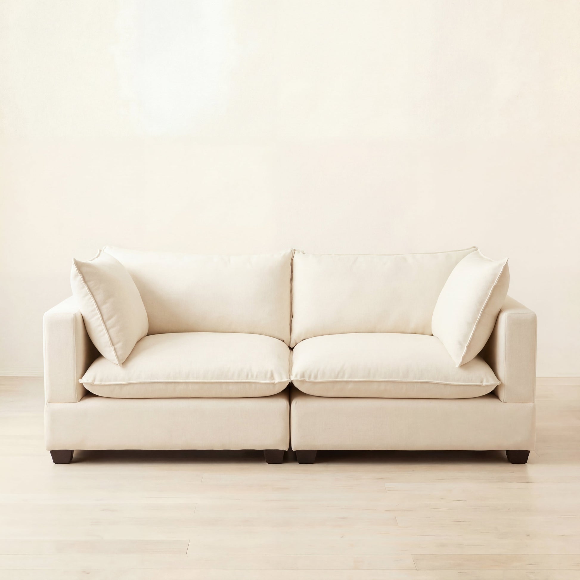alabaster cream color modular sofa with cloud cushions on a light wooden floor and wall