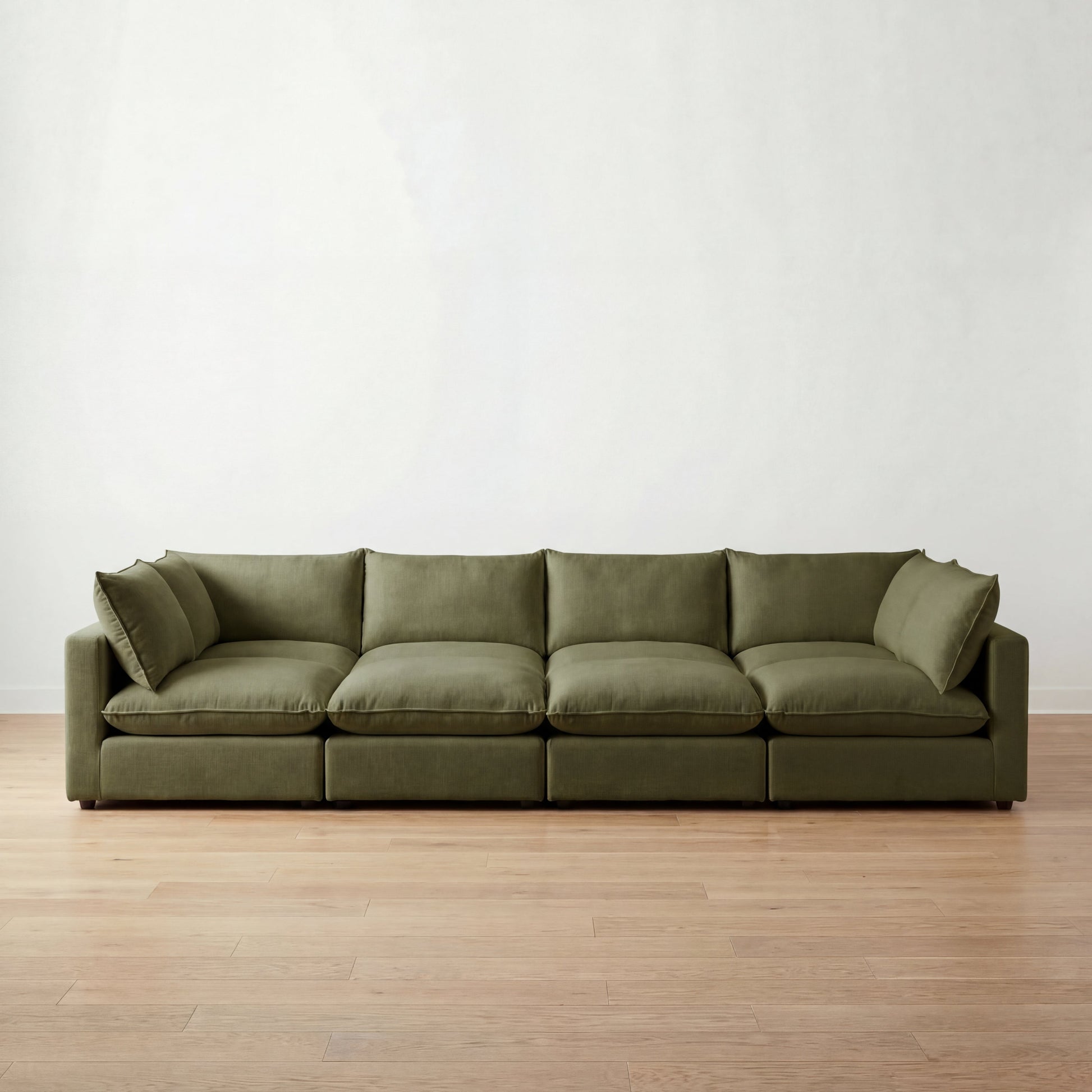 Green cloud sectional pit sofa on a wooden floor with a white wall background