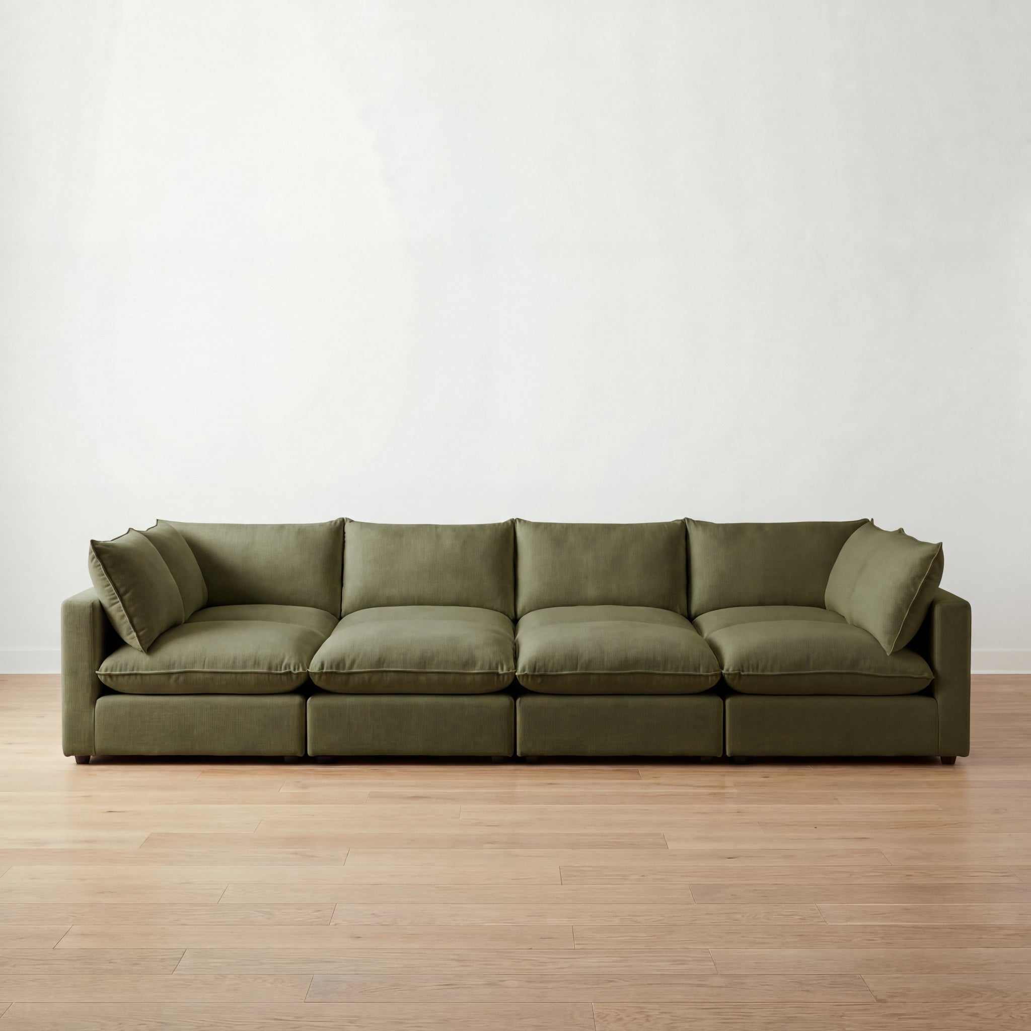 Green cloud sectional pit sofa on a wooden floor with a white wall background