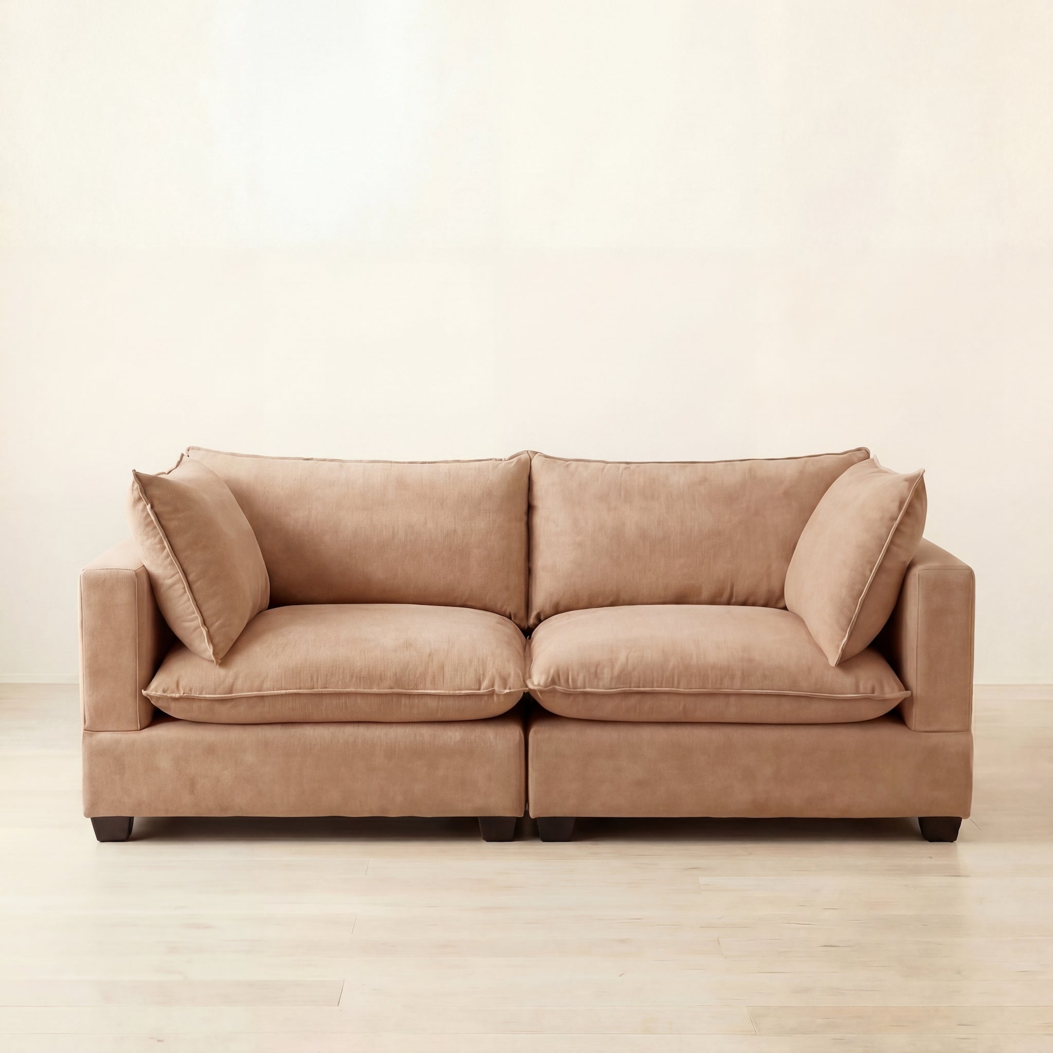 Beige  camel sofa on a light wooden floor with a plain white wall background