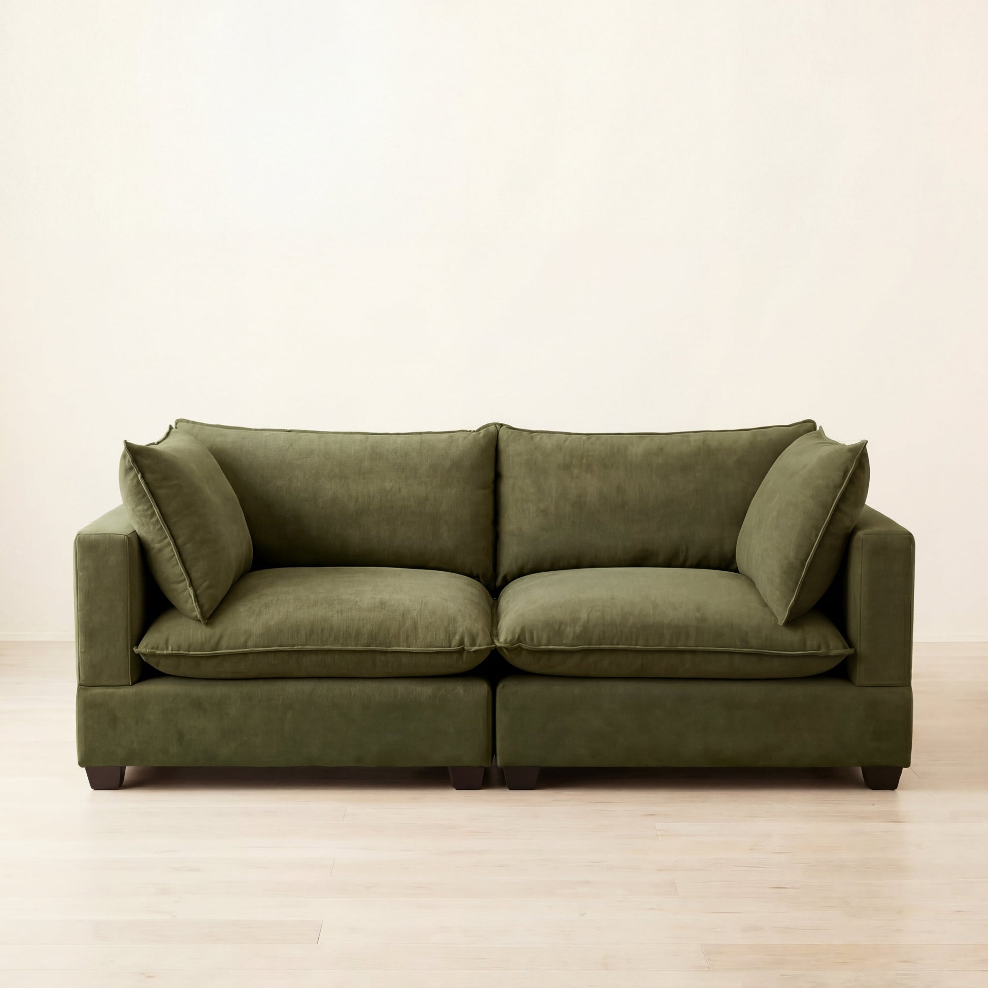Green cloud sofa on a light wooden floor with a white wall background
