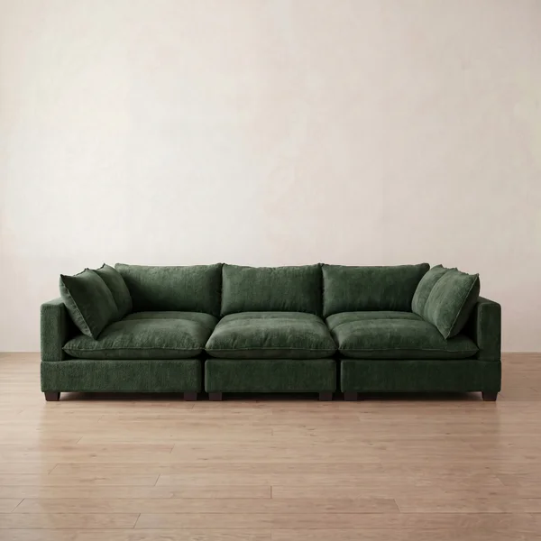 Green sectional sofa on a wooden floor with a beige wall background