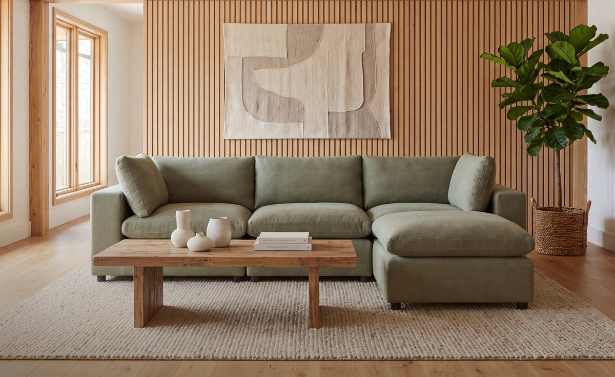 A modern sage green moduar sectional sofa with a reversible chaise lounge in a warm, wood-paneled living room. 