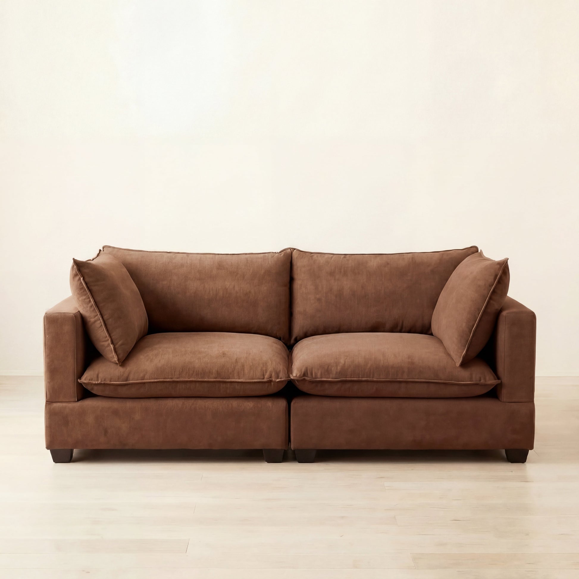 Brown sofa on a light wooden floor with a white wall background