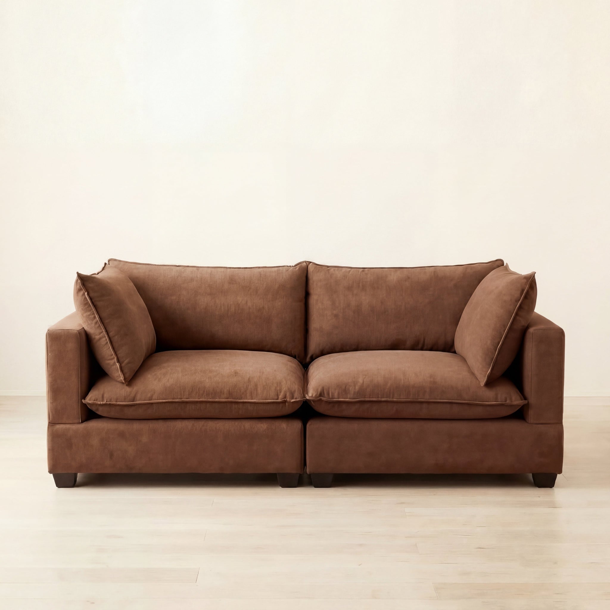 Brown sofa on a light wooden floor with a white wall background